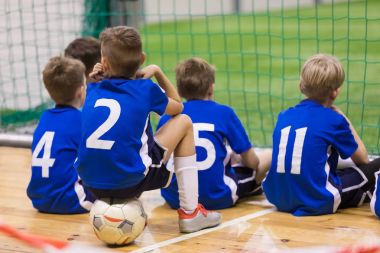 Çocuk futsal takımı. Birlikte oturan genç kapalı futbol oyuncu grubu. Çocuklar okul futbol turnuvası