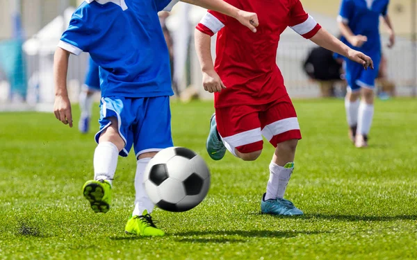 Fotboll Kick; Kör fotboll fotbollsspelare. Fotbollsspelare sparkar fotbollsmatchen; Unga fotbollspelare springa efter bollen. Fotbollsspelare i röda och blå Jersey skjortor sparkar fotboll — Stockfoto