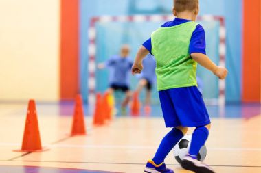 Futbol eğitim top sürme konik matkap. Futbol futsal eğitim çocuklar için. Kapalı futbol bir spor salonunda bir futbol topu ile genç oyuncu. Oyuncu mavi üniformalı. Spor arka plan.