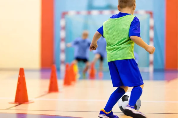 Voetbal training dribbelen kegel boren. Voetbal futsal opleiding voor kinderen. Indoor voetbal talent met een voetbal in een sporthal. Speler in het blauwe uniform. Sport achtergrond. — Stockfoto