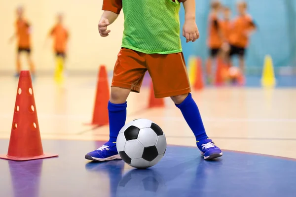 Futbol futsal eğitim çocuklar için. Futbol eğitim top sürme konik matkap. Kapalı futbol bir spor salonunda bir futbol topu ile genç oyuncu. Turuncu Tekdüzen oyuncunun. Spor arka plan. — Stok fotoğraf