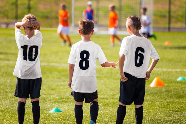 Squadra di calcio per bambini. Ragazzi che guardano la partita di calcio. Torneo di calcio Concorso sullo sfondo. Giocatori di squadra di calcio per bambini nel campo sportivo estivo — Foto Stock