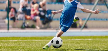 Futbol Futbolu Tekmesi. Futbol sahasında hareketli tekme atan genç bir futbolcu. Arka plandaki Futbol Stadyumu ve Seyircileri