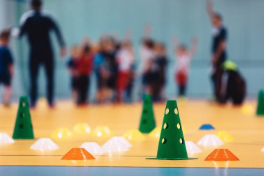 Kış boyunca kapalı alanda futbol antrenmanı. Çocuklar için futbol antrenmanı. Futsal koçu olan çocuklar. Futbolun beden eğitimi bölümü. Renkli ekipman, koni ve işaretlerle gelecek eğitim alanı