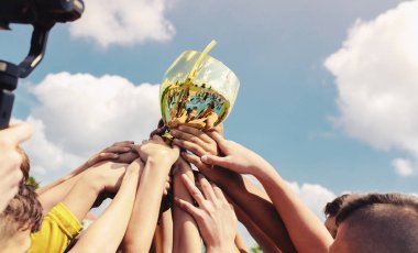 Spor takımındaki çocuklar final maçını kazandıktan sonra altın kupayı kaldırıyorlar. Çocuklar sporda başarıyı kutlarlar. Sporda şampiyonluk.