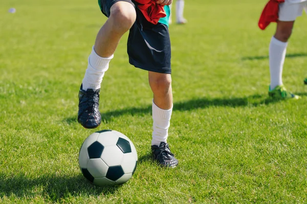 Jeune joueur de football avec ballon blanc et noir classique sur le terrain de football vert herbe — Photo