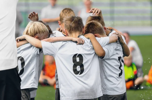 Glückliche Kinder in Sportmannschaften tanzen und feiern Schulmeisterschaft. Jungs kuscheln sich bei sonnigem Sommertag im Team zusammen — Stockfoto