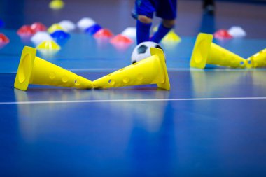 Kış boyunca antrenman yapan kapalı alan futbolcusu. Mavi külahlı futbol antrenman sahası. Çocuklar için kapalı alanda futbol antrenmanı. Okulda futbolun beden eğitimi bölümü