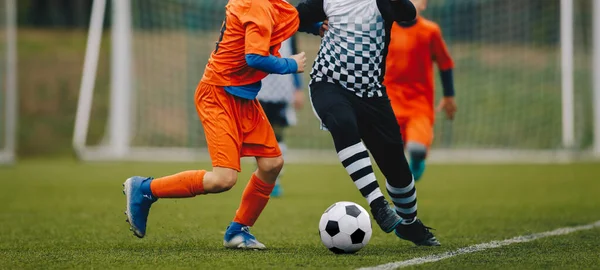 Pojedynek piłki nożnej Juniora. Piłka nożna dla młodych graczy. Chłopcy grający w piłkę nożną na boisku. Stadion piłkarski i trawiaste pole w tle — Zdjęcie stockowe