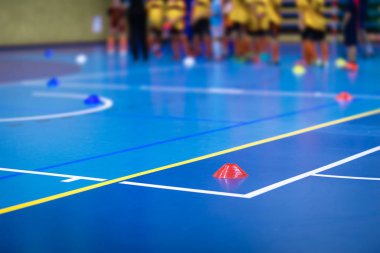 Futsal antrenman sahasında spor takımı. Kış boyunca kapalı alanda futbol antrenmanı. Mavi külahlı futbol antrenman sahası. Çocuklar için kapalı alanda futbol antrenmanı. Futbolun beden eğitimi birimi