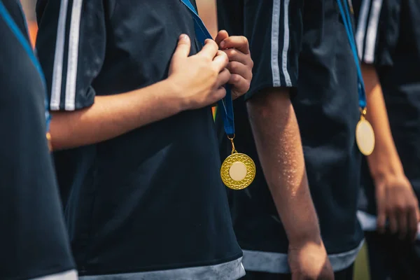 Спортивные детишки с золотыми медалями стоят в ряд во время празднования. Медали на шеях юных спортсменов — стоковое фото