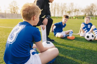 Young Soccer Trainer Coach Explaining Tactic on Team Sports Tactics Board. Children During Soccer Football Coaching Session. Boys in Soccer Team Listening to Coach