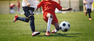 Sports players in football duel run. Footballers running fast and kicking soccer ball on grass stadium during school tournament match