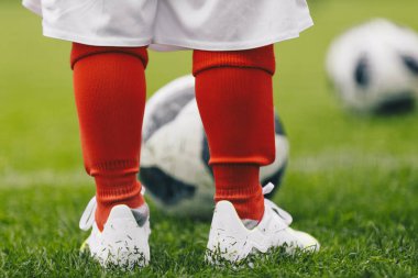 Çim sahasında top oynayan çocuk futbolcunun yakın plan görüntüsü. Futbol takımı ve futbol ayakkabısı giyen bir çocuk.