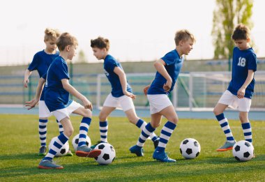 Çocuklar Spor: Çocuklara Futbol Yeteneklerini Geliştirmeyi Öğretmek. Çocuklar için futbol kampı. Çocuklar sahada top sürme pratiği yapıyor. Oyuncular yeteneklerini geliştirir. Toplarla antrenman yapan çocuklar. Futbol slalom talimleri