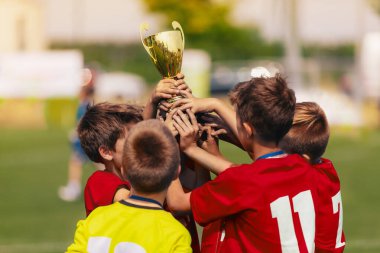 Spor takımındaki mutlu çocuklar yükselen altın kupa kupası