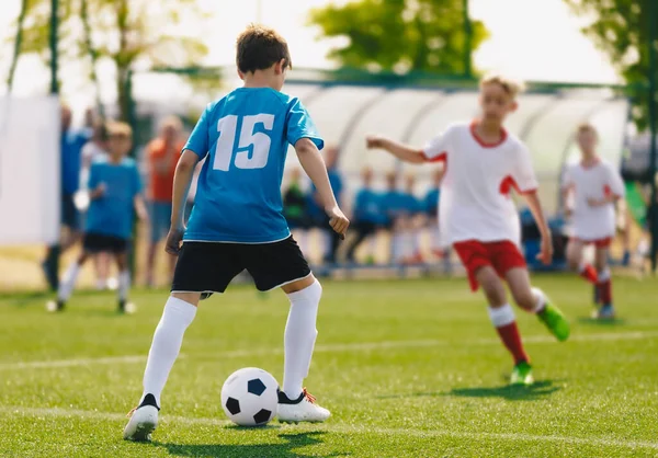 サッカー少年選手権大会出場 子供たちは晴れた日に屋外スポーツをします ジュニアレベルサッカー選手は スポーツ草のフィールドで競争します ぼやけた背景のベンチと代替プレイヤー — ストック写真