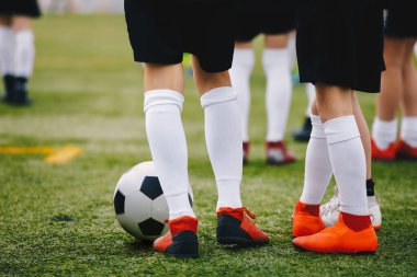 Antrenman sahasında top oynayan futbolcular. Genç sporcular futbol kramponlarıyla ve üniformalarıyla çim antrenman sahasında. Futbolcuların bacaklarının yakın çekimi. Futbol arkaplanı