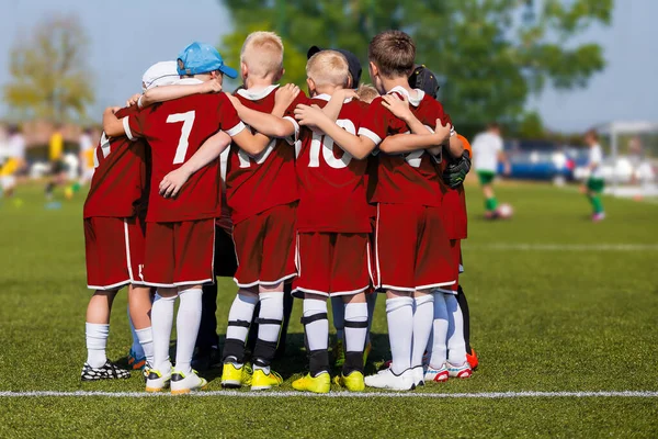 Boys in Sports Team on School Soccer Field. Children Doing Sports in School Team. Kids Team Huddling and Motivating Each Other Before the Tournament Match. Players in Red Jersey Uniforms