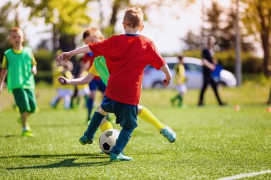 Sahada futbol oynayan ilkokul öğrencileri. Çocuklar futbol sahasında futbol oynuyorlar. Futbol maçında spor giyim bölümünde çocuklar
