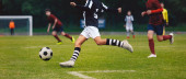 Fußballer läuft und kickt Ball auf einem Spiel. Nachwuchsfußballer spielen Fußballturniere. Fußballwettbewerb zwischen Schülermannschaften