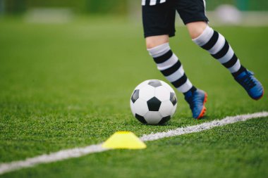 Detaylı futbolcu saha kenarında topa vuruyor. Maçtaki futbolcu. Futbol geçmişini detaylandır. Yeşil çimenlikteki futbolcunun bacaklarına ve ayaklarına yakın durun.