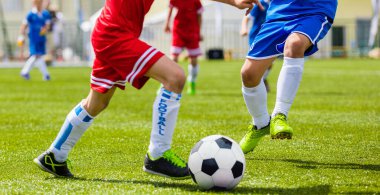 Çocuklar futbol oynuyorlar. Çocuklar topun peşinden koşuyor. Açık havada Junior Level Futbol Turnuvası. Kırmızı ve Mavi Jersey Gömlekli Oyuncular Yarışması