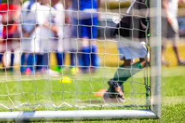 Yan ağlı bir futbol golü. Futbol geçmişi. Futbolcu ve yedek yedek oyuncular arka planda yedek kulübesinde