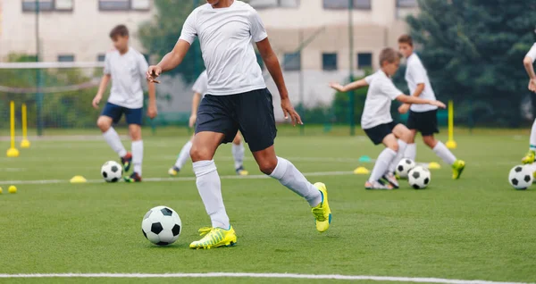 Antrenman sahasında futbolcu. Okulun futbol takımındaki genç çocuklar antrenman yapıyorlar. Çocuklar futbol çalışıyor. Ortaokul spor eğitimi
