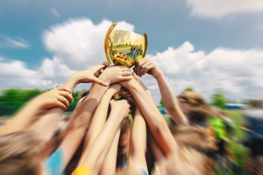Bir grup çocuk dışarıda spor başarısını kutluyor. Erkekler Tutuyor ve Yükselen Altın Kupa Birlikte. Futbol Takımı Altın Kupa Bekliyor