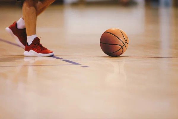 Basketball player walking on wooden court. Basketball over the floor. Basketball sports court
