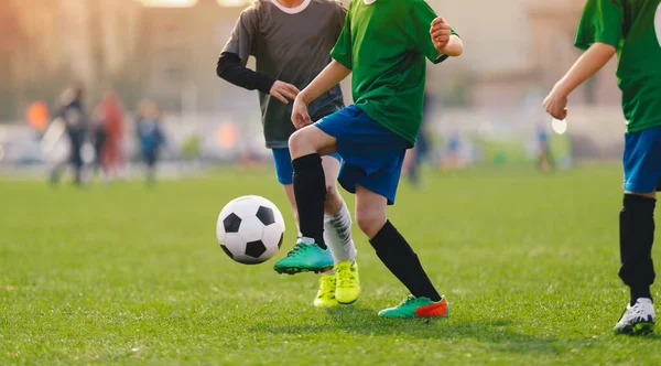Okul futbol maçı. Çocuklar çim tarlasında futbol topunun peşinden koşuyor. Çocuk sporcular arasındaki spor müsabakası