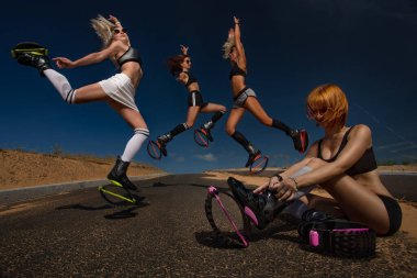 Bir grup kız kangoo atlama botu egzersizi yapıyor, biri de botlarını kontrol ediyor.. 