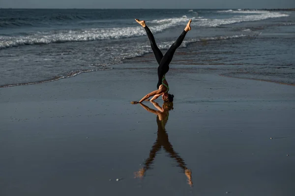 瑜伽头架变化海背景 一个在海滩上表演倒立的女人 — 图库照片