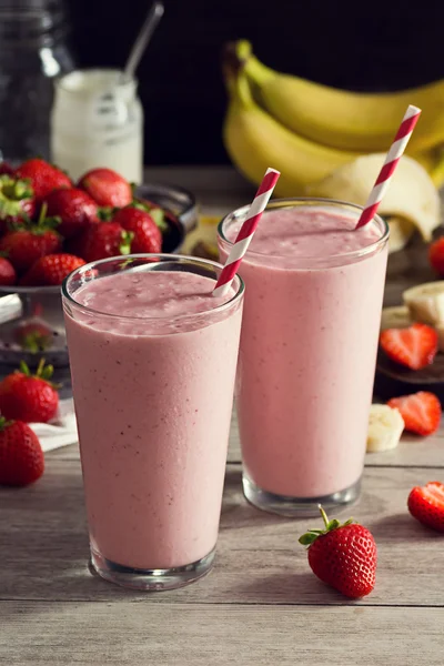 Zwei Erdbeer-Bananen-Joghurt-Smoothies in Gläsern mit Zutaten — Stockfoto