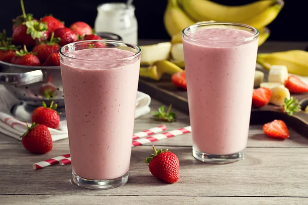 Zwei Erdbeer-Bananen-Joghurt-Smoothies in Gläsern mit Zutaten — Stockfoto