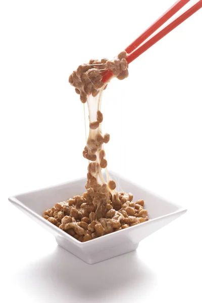 Oppakken van Natto (gefermenteerde sojabonen) met stokjes op witte achtergrond — Stockfoto