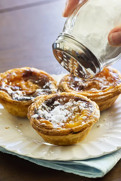 Sprinkling Powdered Sugar on Pasteis de Nata / de Belem — стоковое фото