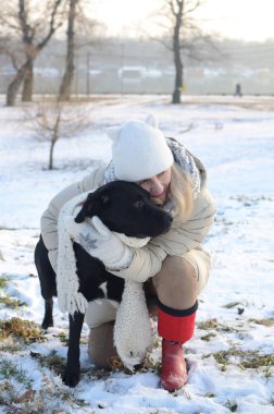 Kadın köpeğe sarılıyor.
