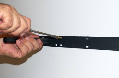 Erkeklerin elleri, duvarda tornavidayla raf tutacağıyla düzüşüyor. Yakın plan.