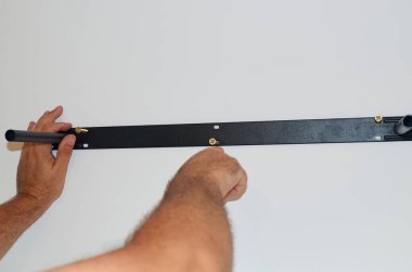 Duvara metal bir raf tutacağı takan adam. Yakın plan.