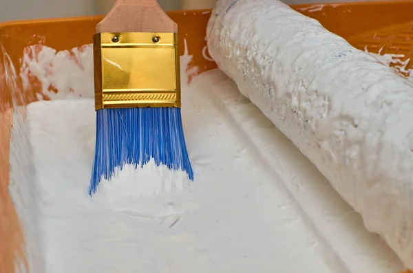 Wooden brush for painting with blue hairs in white color paint