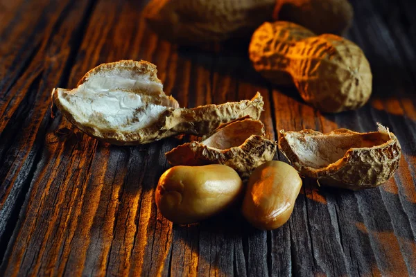 Cacahuètes pelées avec des coquilles dans le fond de la planche vintage — Photo