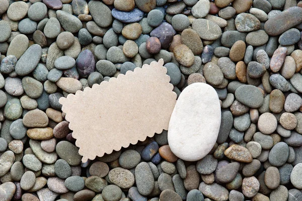 Placa de papel y una piedra blanca sobre un fondo guijarros de mar — Foto de Stock