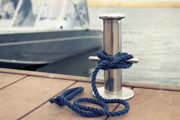 Синя швартова мотузка на металевому боларді на фоні човна — стокове фото
