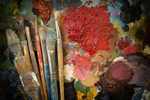Kunstenaar 's oude echte penselen op een donker contrasterende kleurrijke palet — Stockfoto