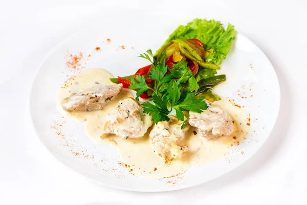 Plate of braised chicken meat with white sauce isolated.