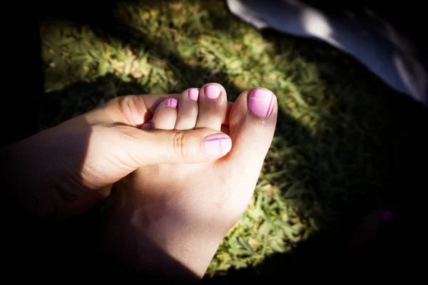 Womans hand and foot on the grass