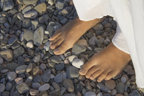 Füße einer jungen Frau am Kiesstrand — Stockfoto