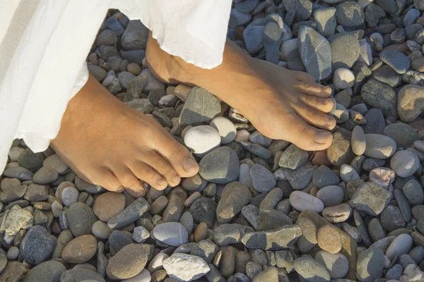 Pies de mujer joven en la playa de guijarros —  Fotos de Stock